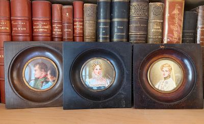 two framed pictures of children on a shelf in front of books