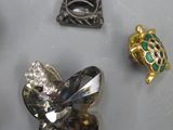 trois broches en argent et en or, de formes et de tailles différentes, posées sur un fond blanc