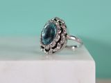 a close up of a ring with a blue topaz stone surrounded by white diamonds