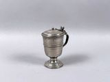une coupe ancienne en argent munie d'une anse, posée sur un fond blanc