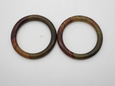 deux bracelets marron et verts posés sur une surface blanche