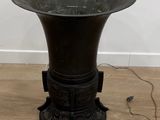 un vase noir posé sur un parquet, près d'un mur blanc