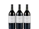 three bottles of red wine sitting next to each other on a white surface