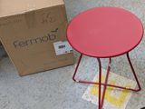 a small red table sitting on the floor next to a cardboard box