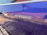 a blue car with a reflection of a house in the window
