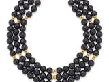 a black beaded necklace with gold accents on a white background