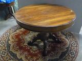 une petite table ronde avec un plateau en bois, posée sur un tapis