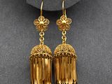 a pair of gold toned earrings on a mannequin mannequin
