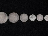 five silver coins are arranged in a row on a black surface