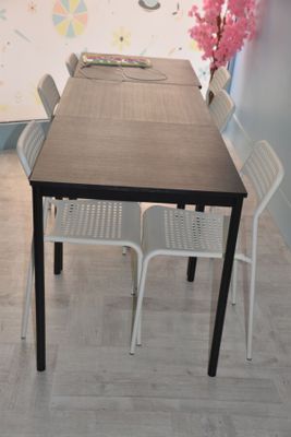 a table and chairs in a room with a clock on the wall