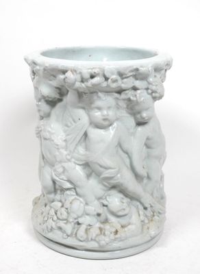 un vase blanc orné d'une statuette, posé sur une surface blanche