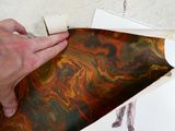 une personne tenant un morceau de papier sur lequel est représentée une peinture