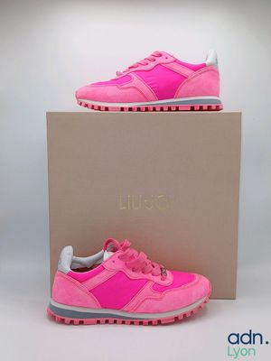a pair of pink sneakers sitting on top of a cardboard box