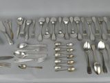 a lot of silverware on a table with a knife, fork, spoon and knife rest