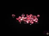 some pink crystals and pearls on a black surface