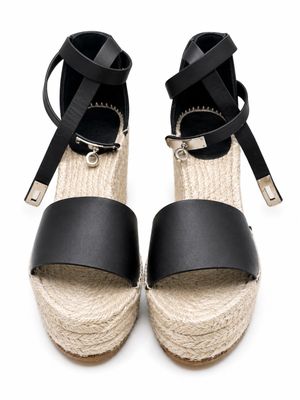 espadrilles en cuir noir ornées de boucles métalliques sur fond blanc