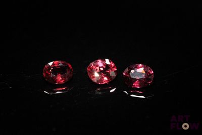 three pink tourmaline gems on a black surface