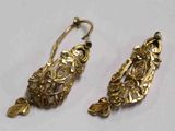 deux paires de boucles d'oreilles en or posées sur une surface blanche