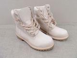une paire de bottes blanches ornées de lacets roses, posées sur une surface grise