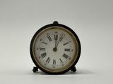 une petite horloge noire avec des chiffres romains
