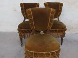 three chairs and a foot stool are sitting in front of a white wall