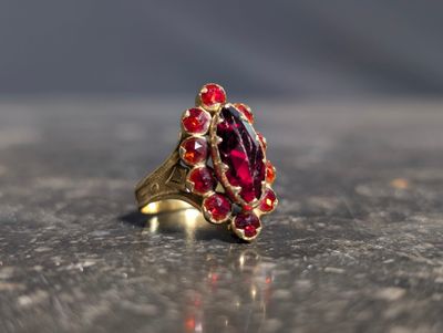une bague en or avec une pierre rouge sur une table