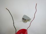 un vase rouge contenant une branche, posé sur une table