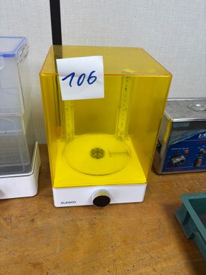 a small yellow machine sitting on a table next to a plastic container