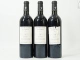 trois bouteilles de vin sont alignées sur une surface blanche