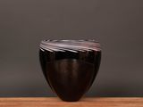 un gros plan d'un vase noir posé sur une table en bois