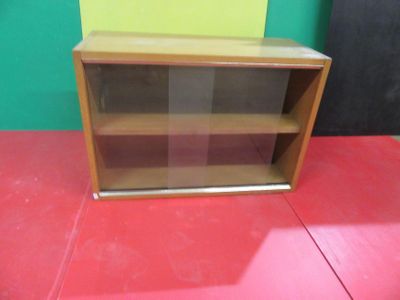 a wooden shelf with a glass door on top of it
