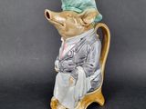 a figurine of a mouse wearing a hat and sitting on a chair