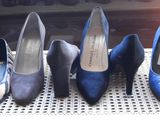four pairs of blue high heels are lined up on a chair