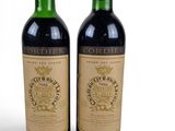 two bottles of wine sitting next to each other on top of a table