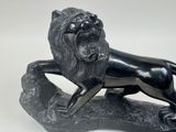 statue of a lion on a rock on a white background