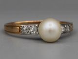un gros plan d'une bague en perle et diamant posée sur une table