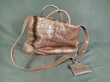 brown crocodile skin purse on green background with a tag