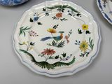 a plate with a bird design on it next to a bowl with flowers