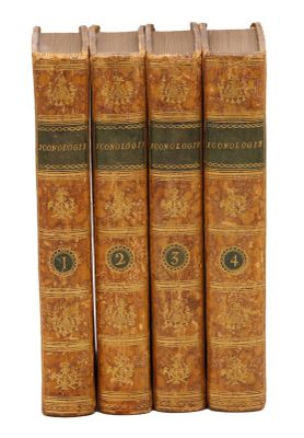 quatre vieux livres posés l'un sur l'autre sur une surface blanche