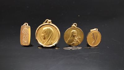 trois médailles d'or et une pièce de monnaie posées sur un fond noir