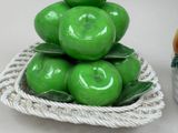 a basket of green apples sitting on a table next to a vase