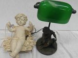 une petite statue représentant un bébé assis sur une table, à côté d'une lampe