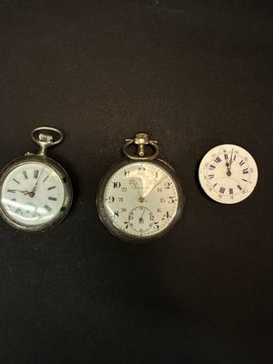 three different types of pocket watches sitting on a black surface