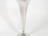 a silver vase that is sitting on a white surface