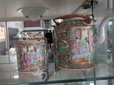 a glass shelf with two cups and a teapot on it