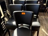 Plusieurs fauteuils en cuir noir sont alignés en rang devant une fenêtre