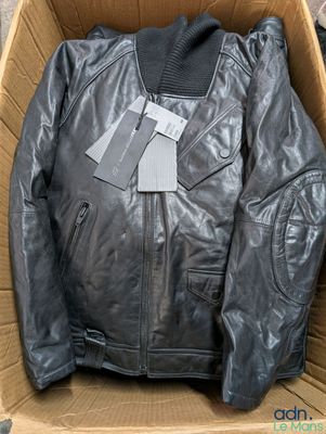 une veste en cuir noir dans une boîte en carton posée par terre