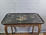 une vieille table au plateau noir posée sur un parquet
