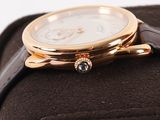 a close up of a gold watch on a black case