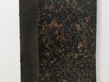 an old book sitting on top of a table next to a white wall